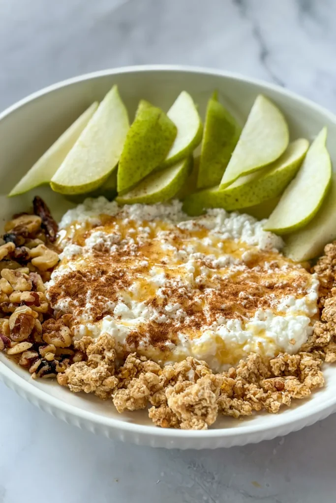 A cottage cheese, pear, granola nd walnut plate. 