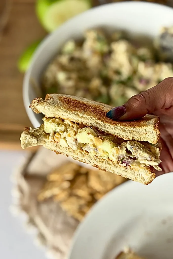 A close-up of a honey mustard chicken salad sandwich in someone's hand.
