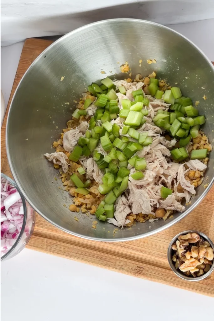 The ingredients for the chicken salad in a mixing bowl on a counter.