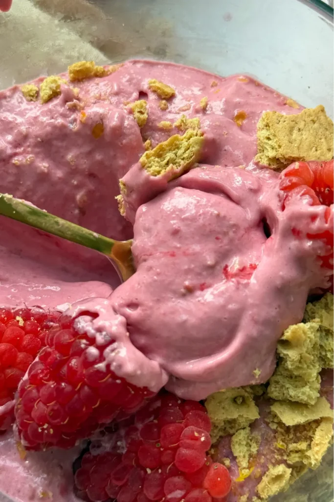 A close-up of the creamy frozen protein whip in a bowl topped with raspberries.