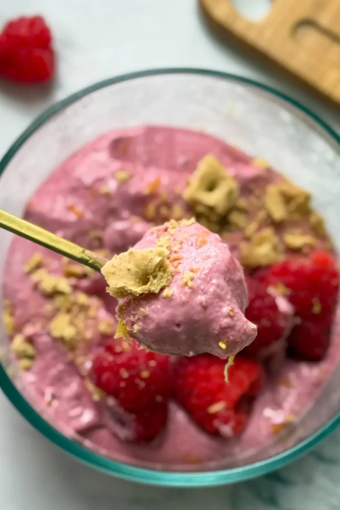 A close-up of a spoonful of lemon raspberry whip above a bowl.