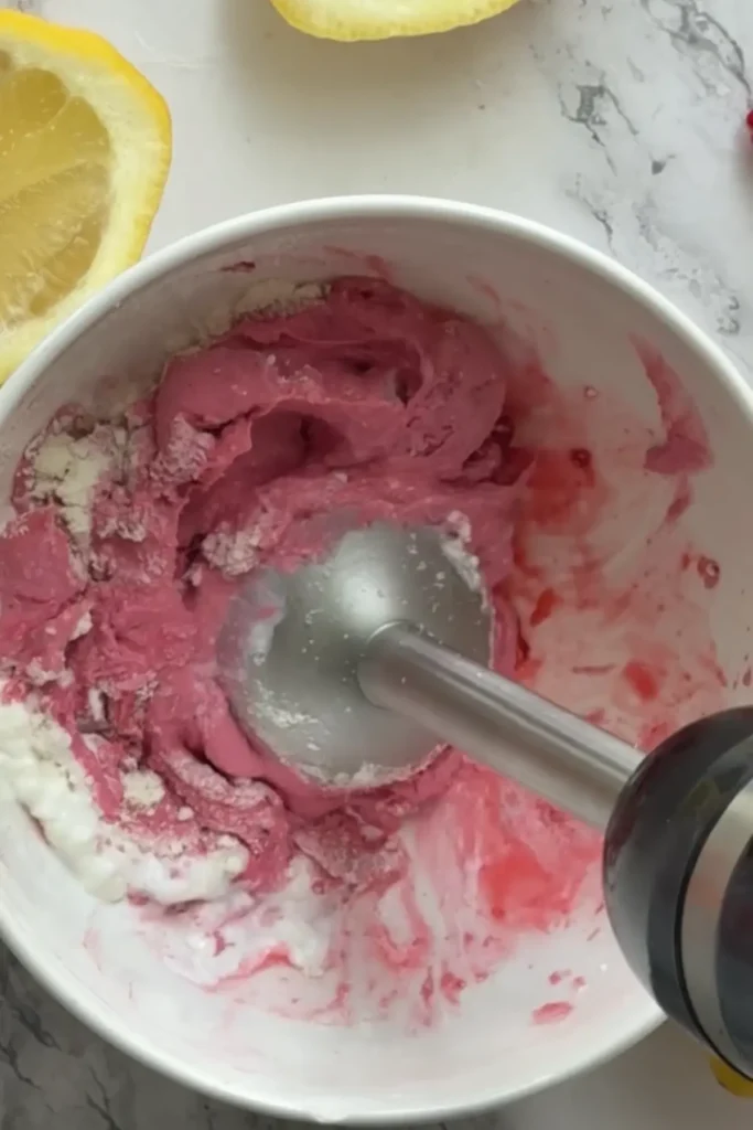 An immersion blender blending the protein whip ingredients in a bowl.
