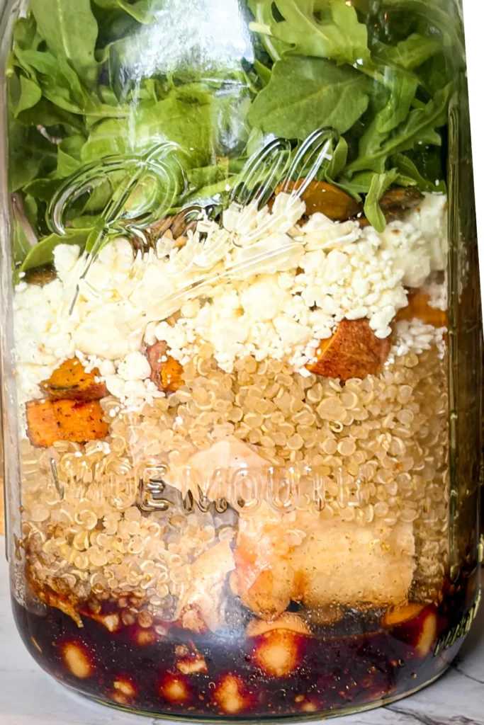 A close-up of all of the different layers in the meal prep maple balsamic salad jars.