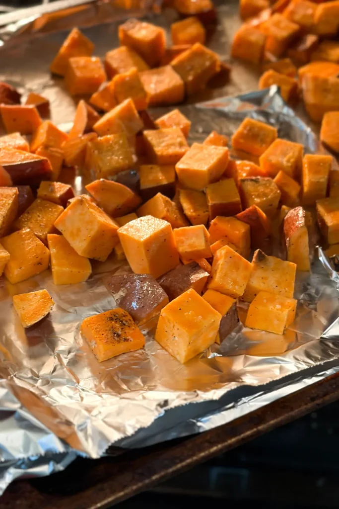 Cubed and raw potatoes on a sheet pan covered in aluminum foil.