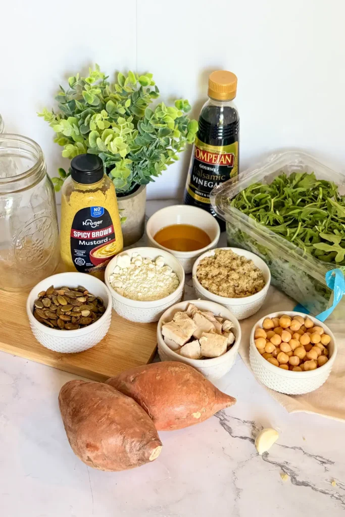 All of the ingredients for the meal prep chicken grain salad jars with balsamic and maple dressing on a counter.
