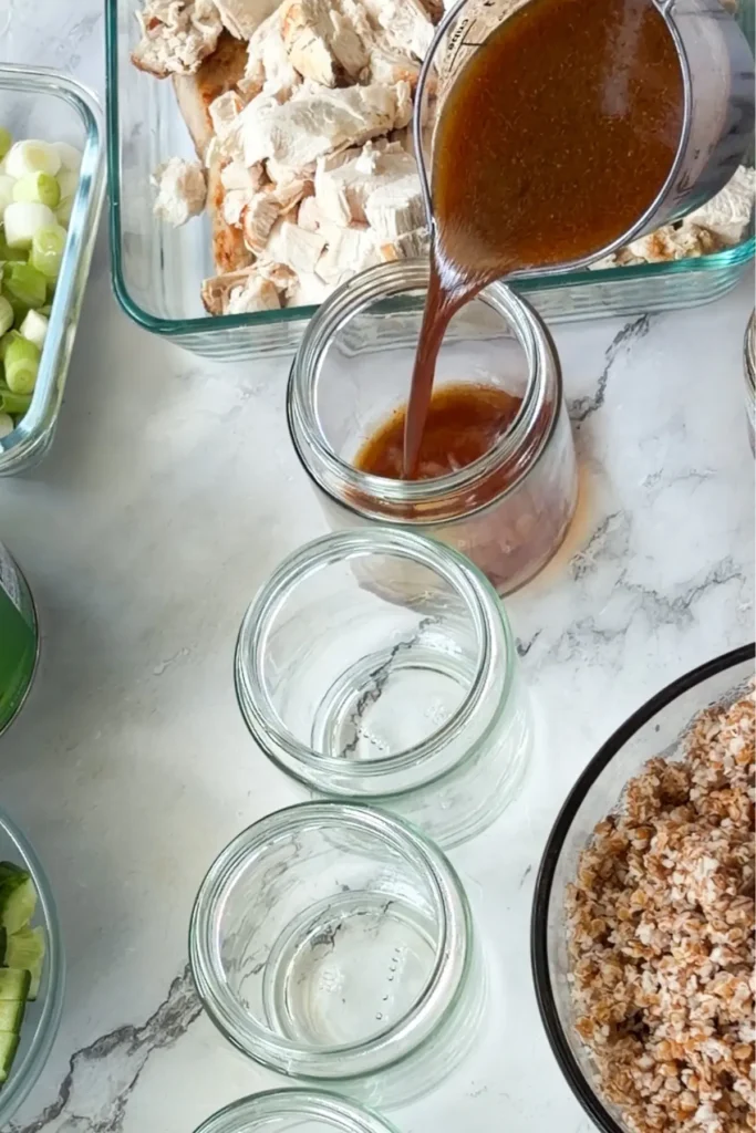 Pouring the dressing into the glass jars on a counter.