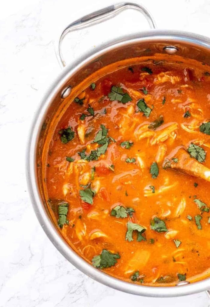 A birds-eye view of curried pumpkin chicken soup in a pot.