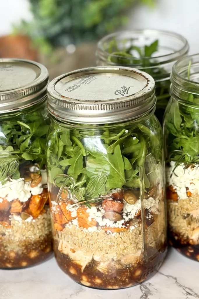 Three maple balsamic salad jars on a counter.