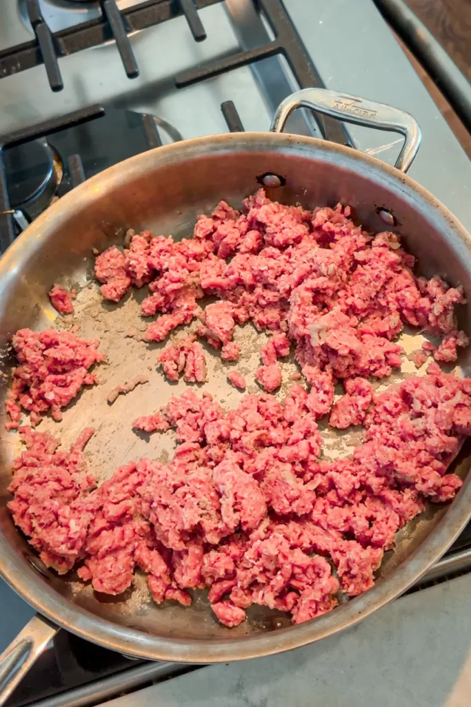Raw ground turkey cooking in a pan on the stove.