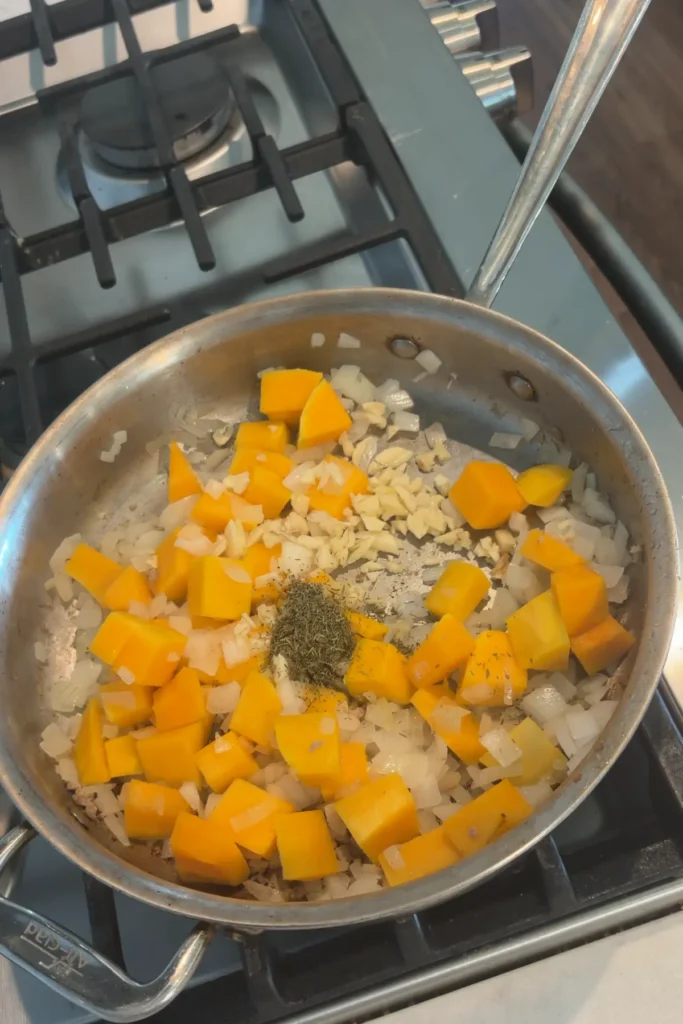 Butternut squash and onions cooking together with the sage on the stove.