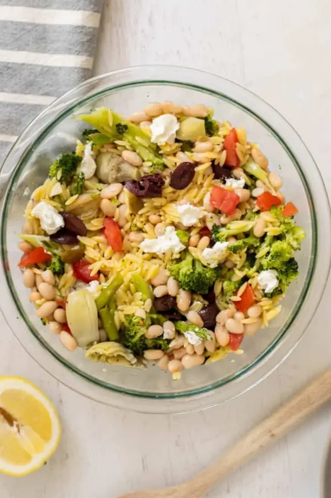 A birds-eye view of a lemon orzo Greek salad on a table.