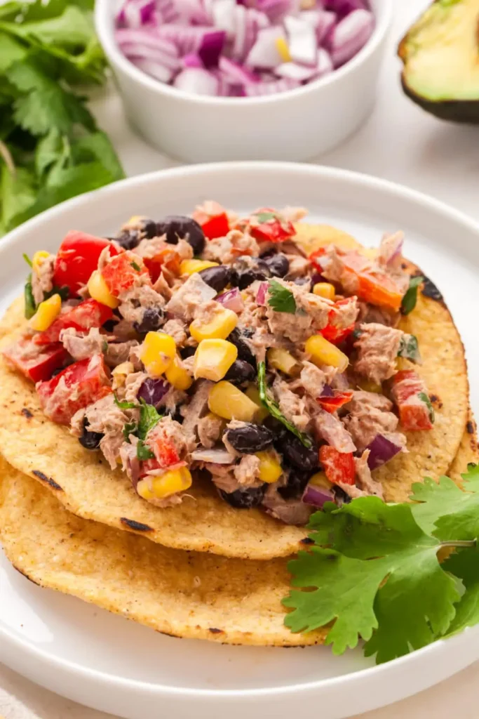 Tuna Mexican salad in a taco shell on a plate.