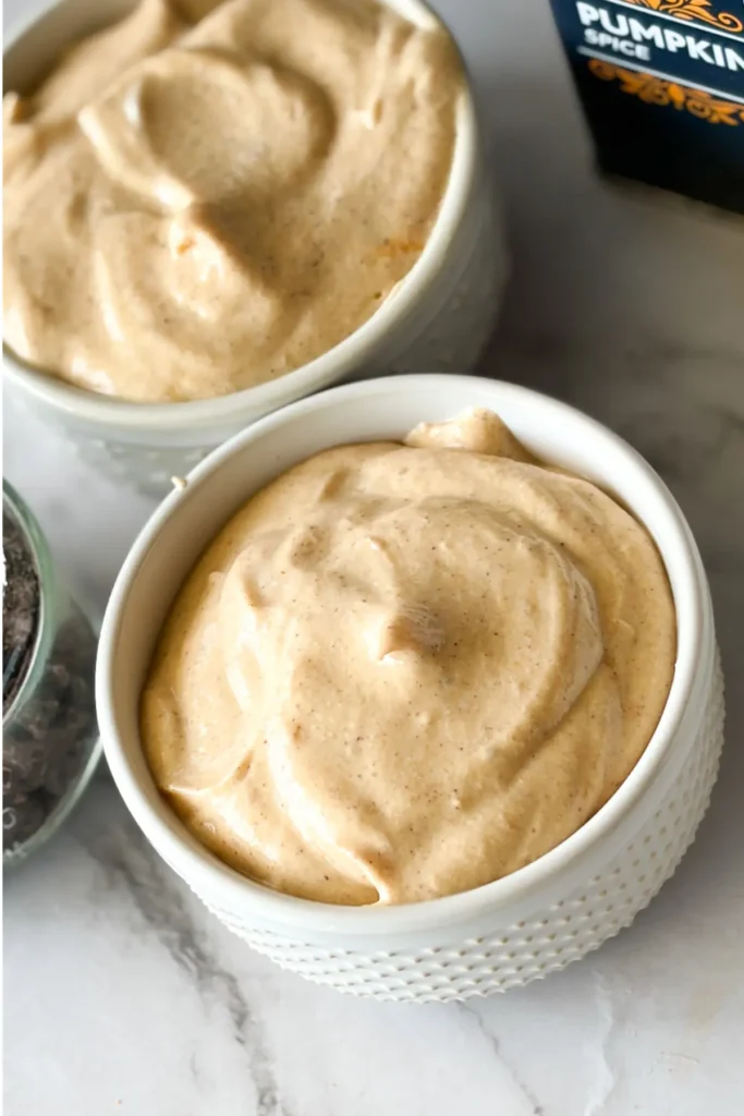 Two small ramekins with the creamy cannoli dip divided between them.