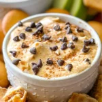 A close-up of the pumpkin cannoli dip in a small white ramekin surrounded by waffle cone chips.