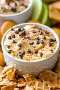 A close-up of the pumpkin cannoli dip in a small white ramekin surrounded by waffle cone chips.
