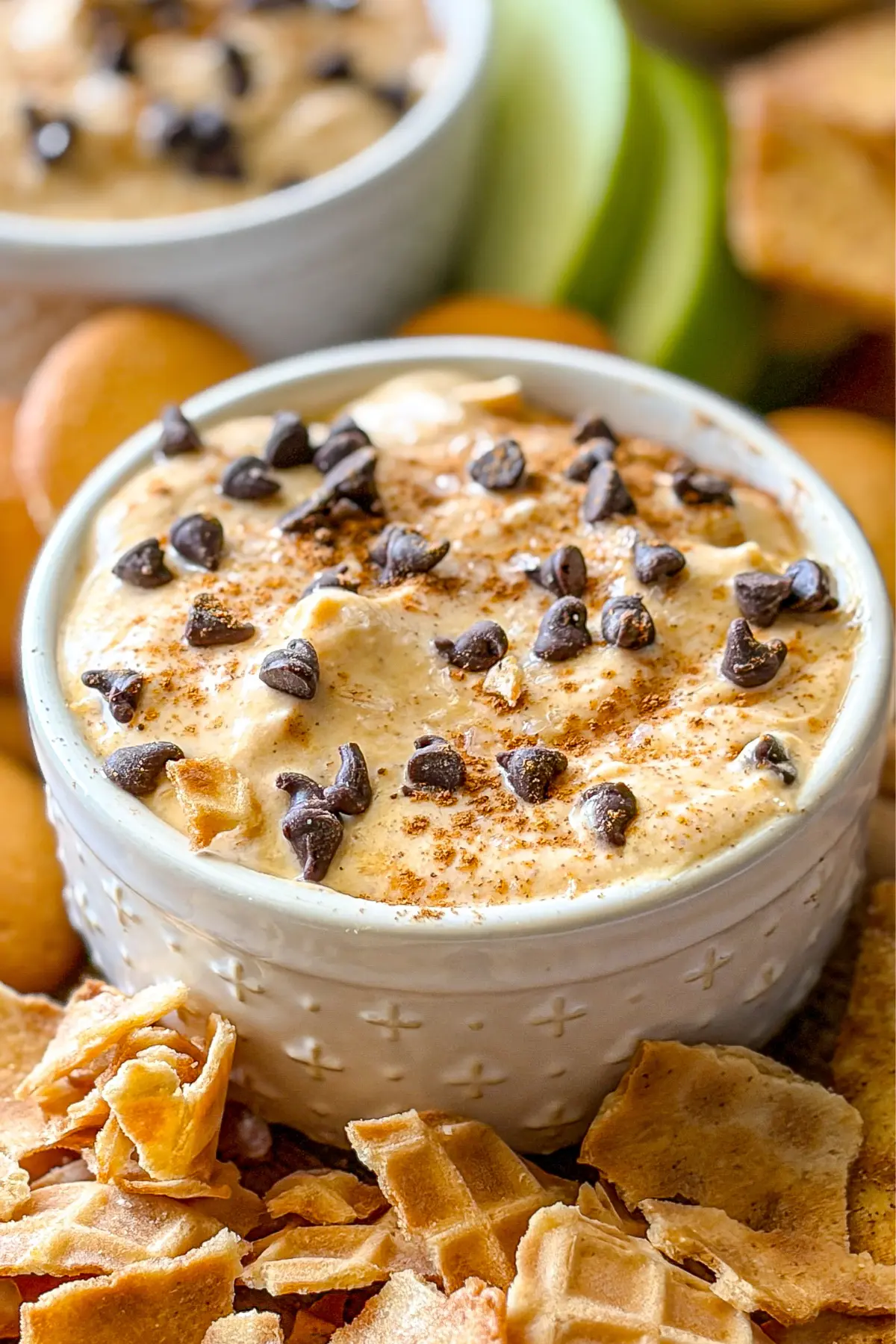 A close-up of the pumpkin cannoli dip in a small white ramekin surrounded by waffle cone chips.