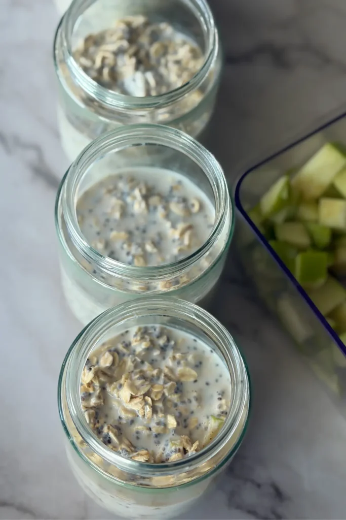 Four jars filled with overnight oats base on a counter before refrigeration.