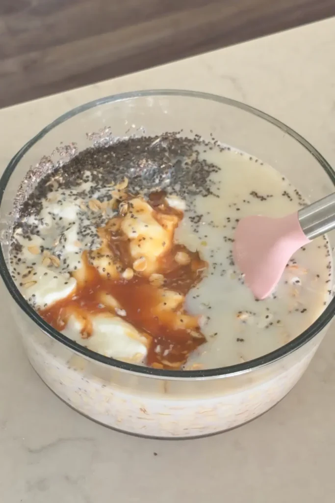 Ingredients for the overnight oats base in a bowl with a spatula in it.