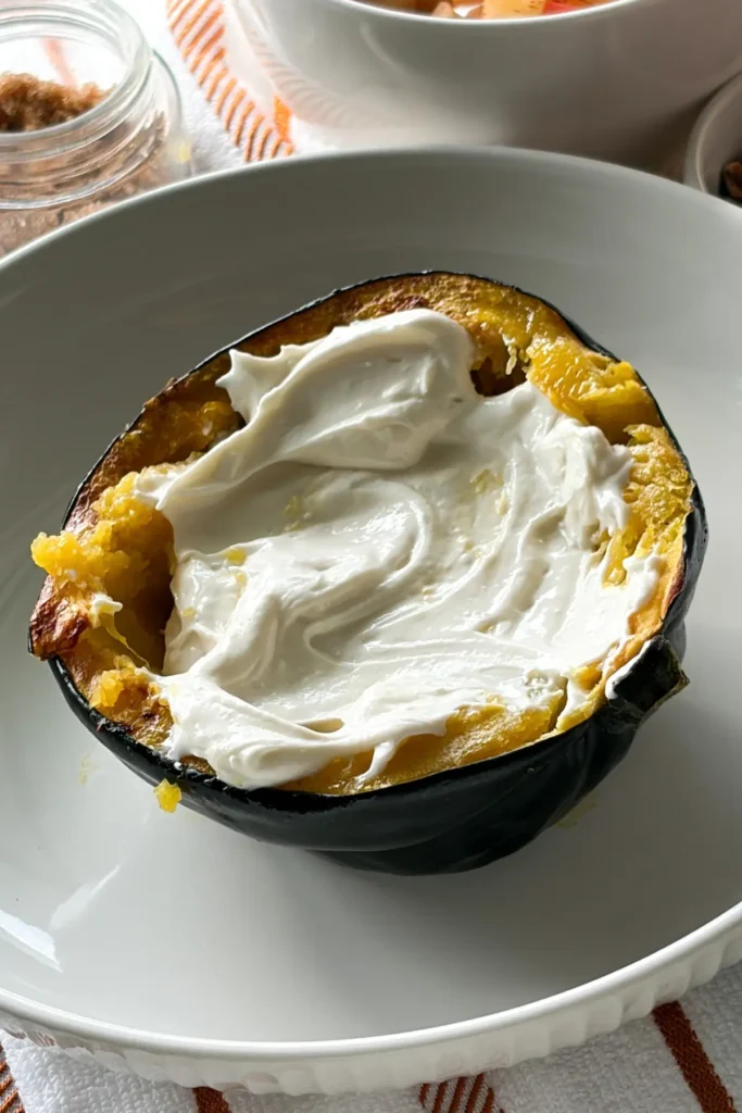 A squash halve on a white plate filled with vanilla cheesecake filling.