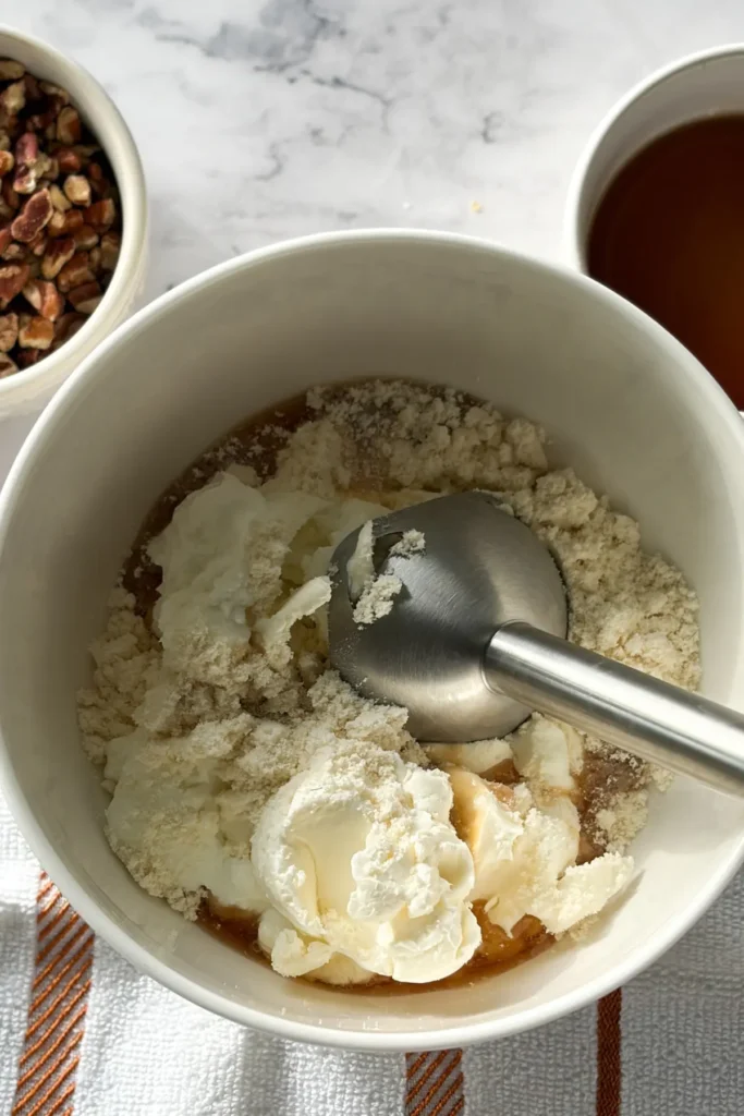 The ingredients for the protein cheesecake filling in a bowl with an immersion blender in it.