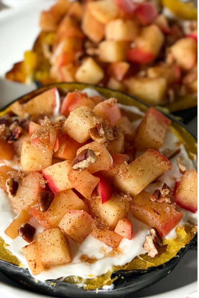 Two acorn squash breakfast boats fully assembled on a white plate.