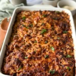 An Italian quinoa casserole with ground turkey in a white glass baking dish right out of the oven on a counter with a crispy cheesy top.