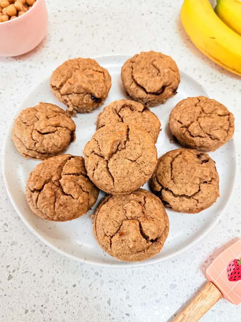 A plate of chickpea muffins on a table next to a bunch of bananas.
