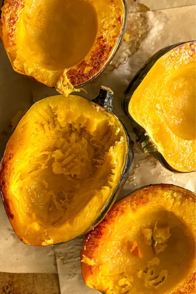 A birds-eye view of the roasted acorn squash with flesh side up on a baking sheet after roasting.