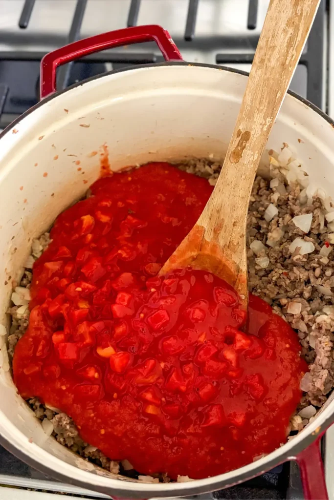 Pouring the tomatoes into the Dutch oven.