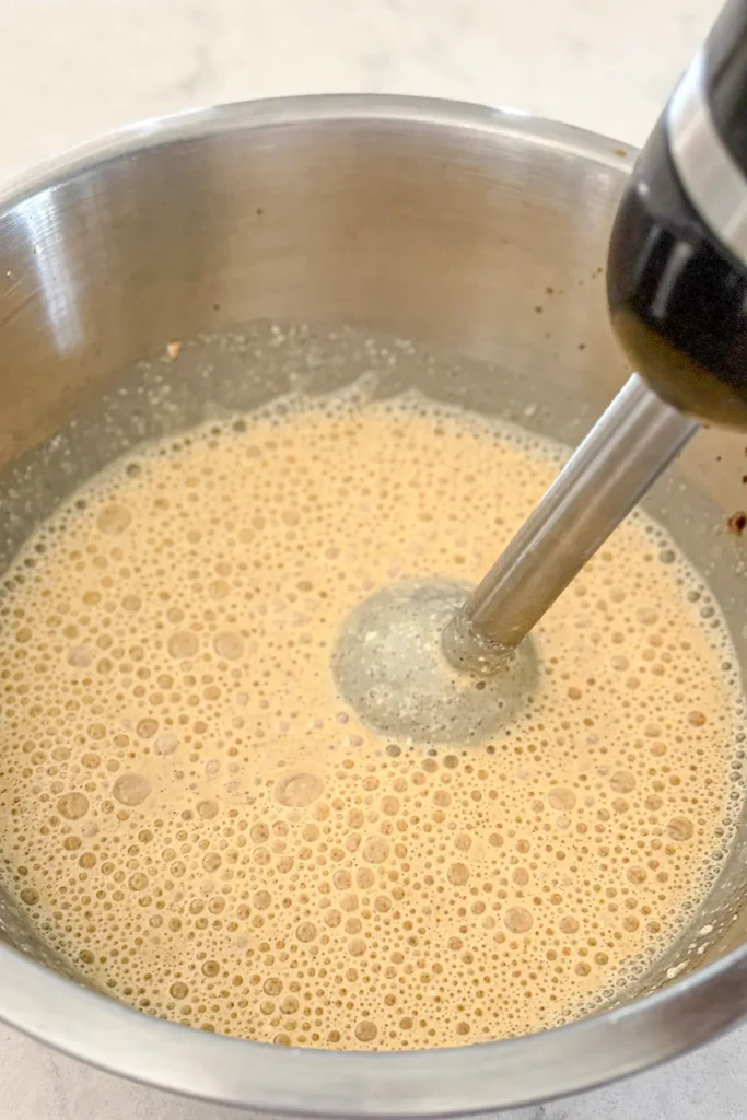 An immersional blender blending the eggs, cottage cheese and spices.
