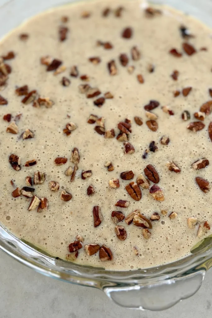The maple pecan mixture poured into a glass baking dish and topped with pecans before going into the oven.